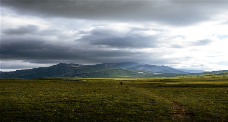 Photo of green grass field near mountain under white clouds by Gleb Lucky on pexels.com